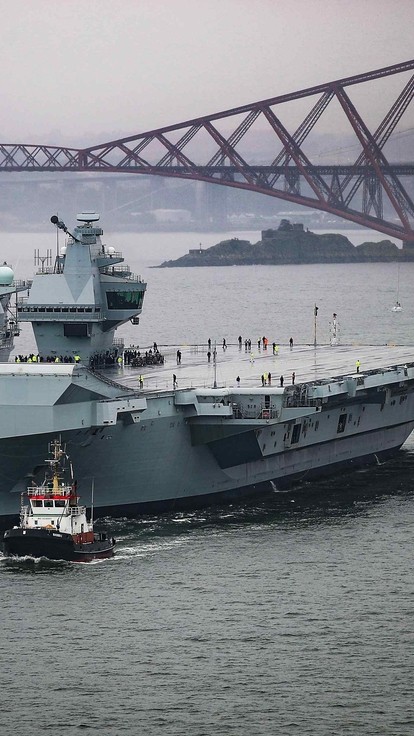 Britain’s newest aircraft carrier, The Prince of Wales, pictured sailing from Rosyth Dockyard for the very first time. Eight years after her steel was cut, the 65000-tonne warship heads under the iconic Fourth Bridge to begin her initial sea trials.